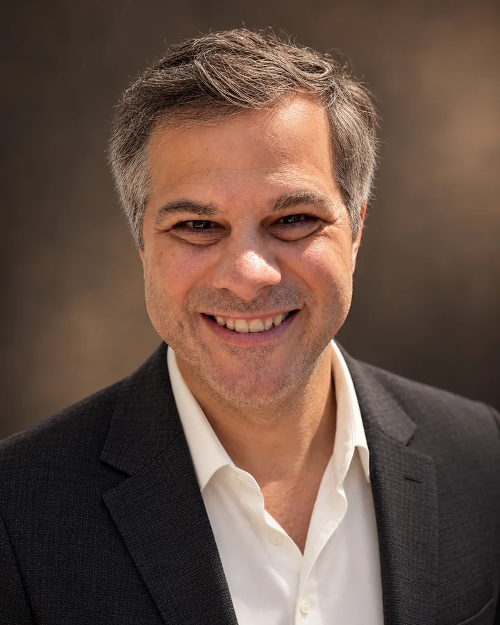 Portrait of Rob Iula, smiling, in a charcoal blazer and white shirt.